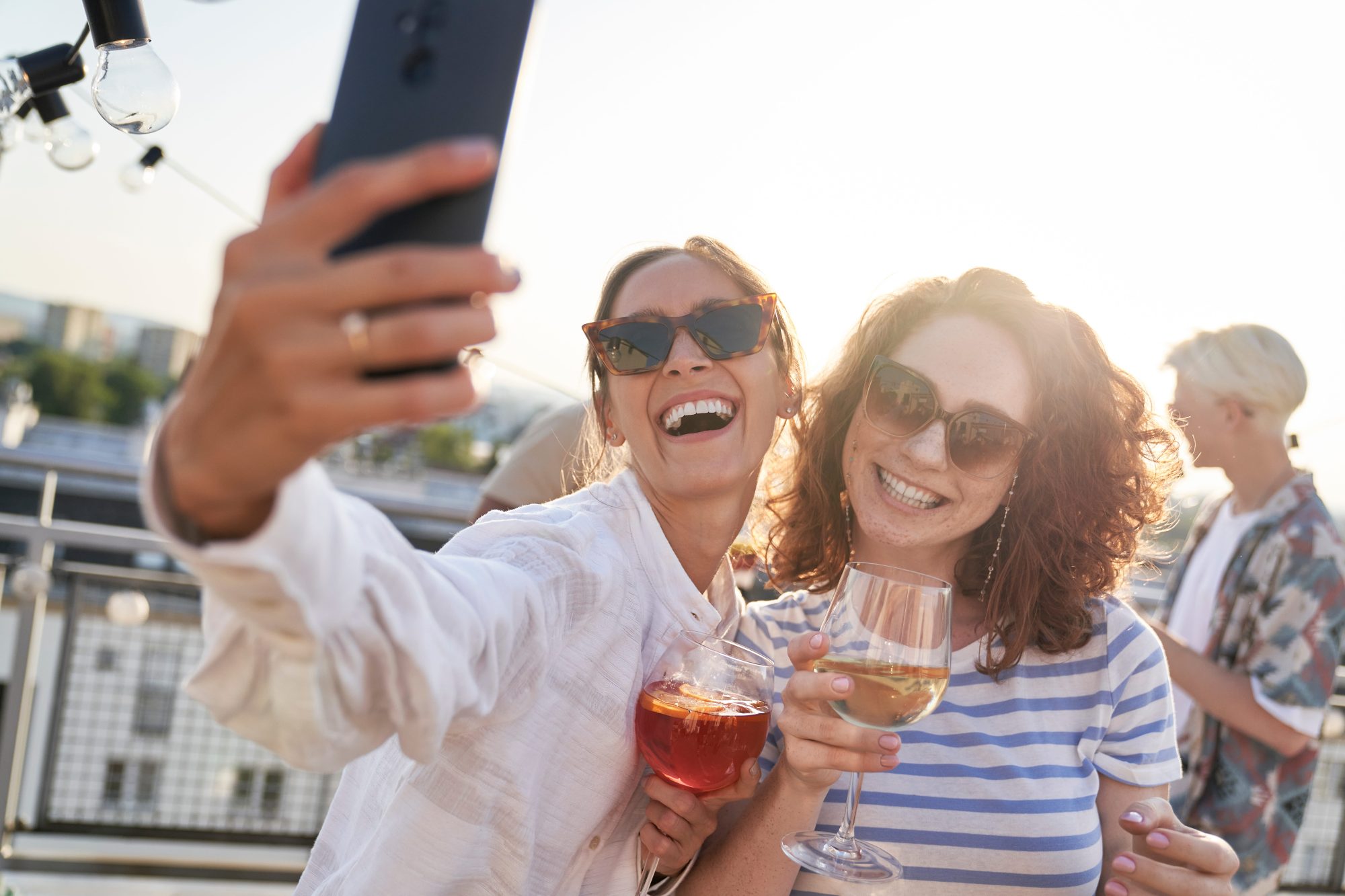Two wedding guests taking a smartphone selfie while celebrating